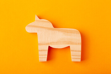 A figurine of a horse or unicorn carved from solid pine with a hand jigsaw. On a yellow background