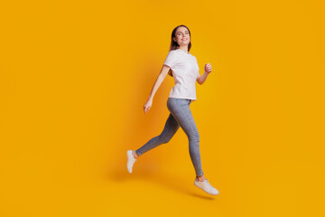 Fototapeta na wymiar Photo of active sportive teen lady jump run wear white t-shirt posing on yellow background