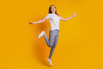 Fototapeta na wymiar Photo of crazy energetic lady jump have fun wear white t-shirt posing on yellow background