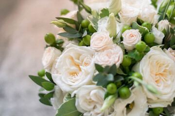 Beautiful bridal bouquet of white flowers and greenery, decorated with long silk ribbon lies on a gray textural background. Copy space