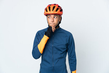 Young cyclist Brazilian man isolated on white background having doubts and thinking