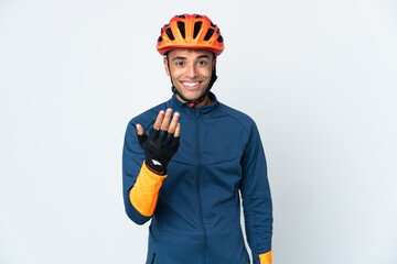 Young cyclist Brazilian man isolated on white background inviting to come with hand. Happy that you came - obrazy, fototapety, plakaty
