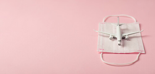 Fototapeta na wymiar Closeup photo of plane model on medical mask isolated pink background