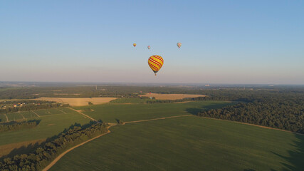 Aerial view Hot air balloons in sky over fields in countryside, beautiful sky and sunset. Aerostat fly over countryside. © Alex Traveler