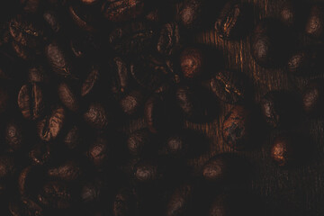Roasted coffee beans on the old dark wooden background for wallpaper or decor. Toned
