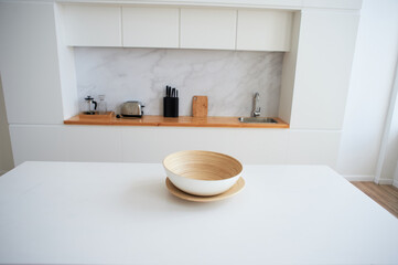 Fototapeta na wymiar White countertop with a large light bowl for salad. Kitchen in the studio. Decor of a stylish room.