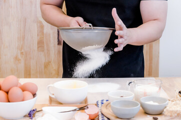 Chef sifts flour through a sieve on a wooden table,Flour sifting through a sieve for a baking,Baking concept