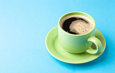 Hot fresh coffee with foam in the green cup on a color background