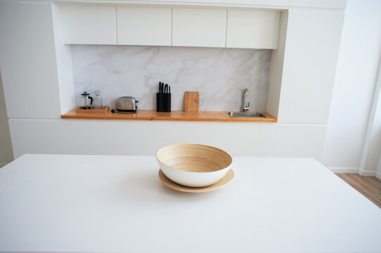 White countertop with a large light bowl for salad. Kitchen in the studio. Decor of a stylish room.