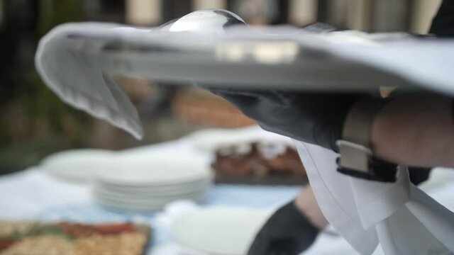 The waiter serves the table. Spoons, forks and knives to lay out on plates according to the rules of etiquette. Service staff in the restaurant with gloves. Cutlery close up. Banquet service.