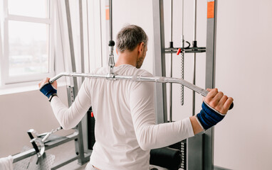 Fototapeta premium a man performs exercises in the gym on a simulator. back training