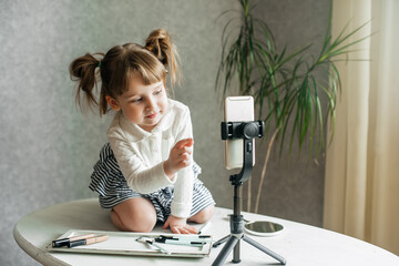cute caucasian baby girl video blogger, phone on a tripod.