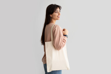 Portrait of young woman standing with blank canvas tote bag