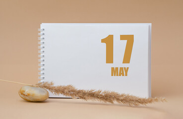 may 17. 17th day of the month, calendar date. White blank sheet of notepad, stones, dry sprig of...