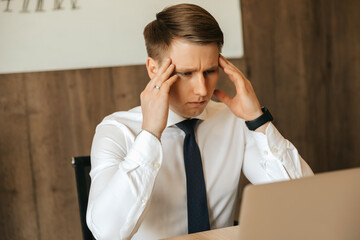 Headache, workload, a hard task, a man who is tired at his workplace. Working at a computer remotely.