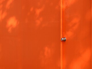 orange door of wall with shadow of tree background