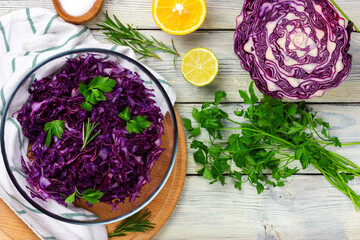Purple cabbage salad in a glass bowl. The process of preparing a vegetarian salad. View from above.