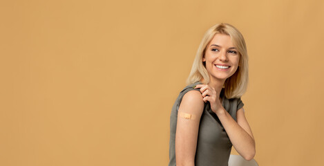 Vaccination saves lives. Happy woman getting vaccinated immunity to covid-19, posing over beige...