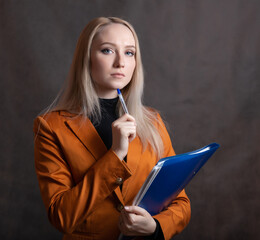Business woman portrait with blue folder in hand on dark background.