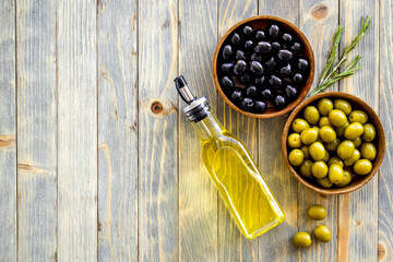 Olive oil in bottle with green and black olives, top view
