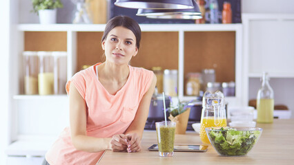 Beautiful young woman using a digital tablet in the kitchen