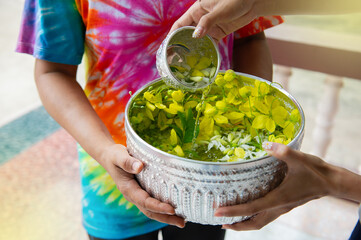Thai women wearing colorful shirts holding a bowl of flowers and water in a bowl, Thai Songkran Festival.