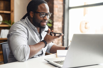 Busy African-American businessman in glasses with dreadlocks working in office, sitting at desk,...
