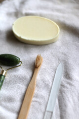 Jade face roller, wooden toothbrush, glass nail file and bar of soap. Sustainable body care products. Selective focus.