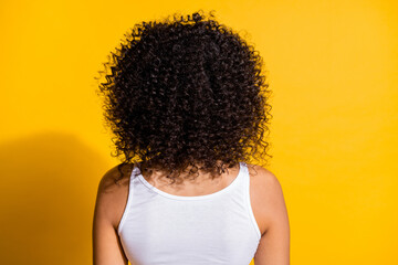 Rear portrait of dark skin girl have nice hair curls wear tank-top isolated on vivid yellow color...