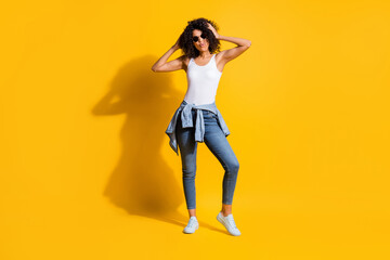 Full length photo of pretty dark skin girl arms touch wavy hairdo free time isolated on yellow color background