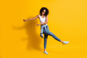 Fototapeta na wymiar Full body photo of dark skin trendy woman wear casual outfit jacket on waist sunglass dance isolated on yellow color background