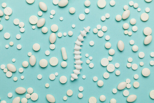 Human spine model with pills on blue background.