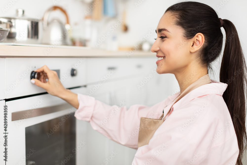 Wall mural woman using stove cooking food in kitchen