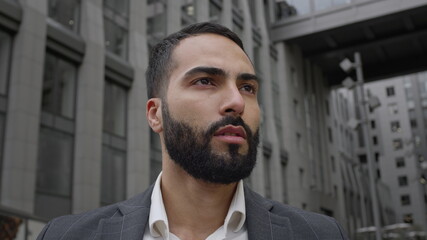 Face Of Young Man On The Street. He Looks Serious. Dressed Man In Business Style. Behind Tall Building.