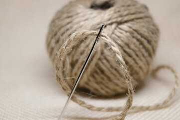 a tangle of thread rope with a large steel needle environmentally friendly material craft embroidery against the background of white canvas