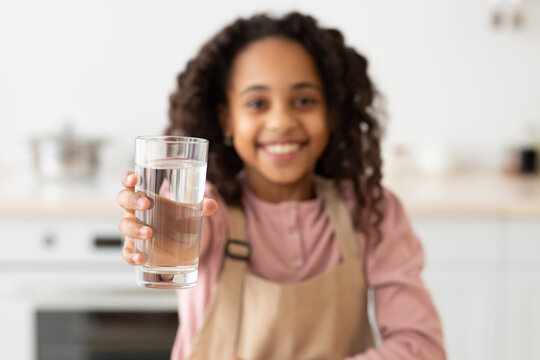 African American curly girl holding glass of water