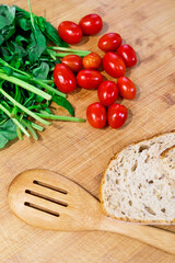 vertical view of mediterranean cooking ingredients on top of a wooden platter at home. Spanish breakfast preparation with fresh vegetables. Food and cooking concept.