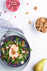 Fresh and healthy salad with arugula, gorgonzola cheese, pomegranate and pears.