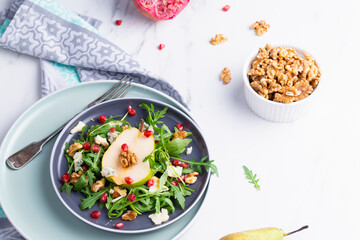 Fresh and healthy salad with arugula, gorgonzola cheese, pomegranate and pears.