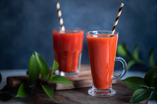 Two glasses of red homemade fresh tomato juice on dark rustic background, selective focus