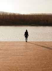 Woman in black coat enjoying sunset near river