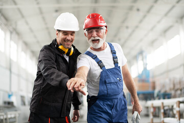 Portrait of workers in factory. Successful team puting their hands together.