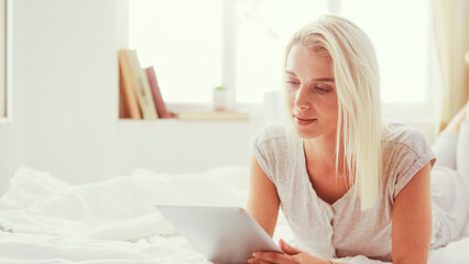 Girl holding digital tablet with blank screen and smiling at camera in bedroom