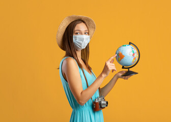 Young woman in protective face mask holding globe