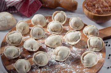 Raw dumpling with chopped meat. Preparation dumplings on wooden board with flour.Russian food.