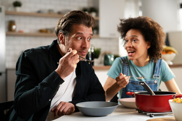 Boyfriend and girlfriend eating lunch together at home. Husband and wife enjoying in delicious food.