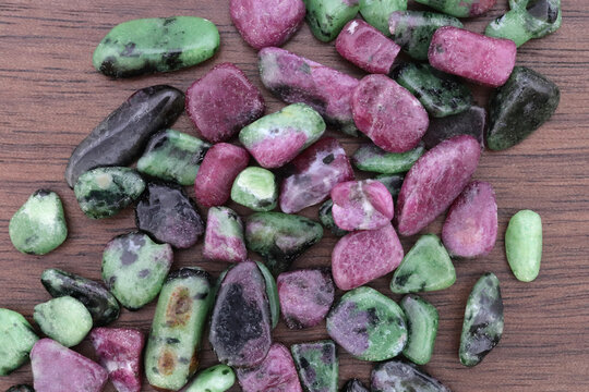 Ruby zoisite jewel stones heap up texture on brown varnished wood background