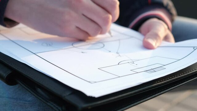 Football coach explaining the goal combination to the players on a piece of paper, close-up
