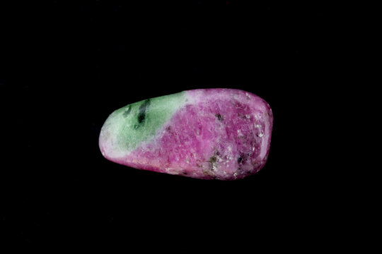 Ruby zoisite jewel stone texture on black background. Macro closeup.