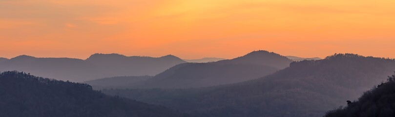 mountain layers after sunset during golden hour, orange sky, distant fog